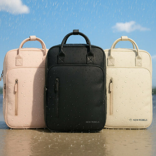 je ziet drie mooie new rebels tassen die in de regen staan maar omdat ze waterafstotend zijn liggen de druppels erop